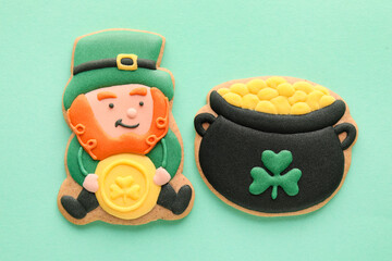 Tasty decorative gingerbread cookies for St. Patrick's Day celebration on green background