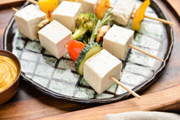 Plate with grilled tofu cheese skewers and mustard on table, closeup