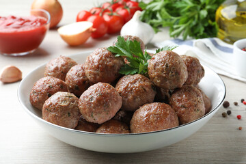 Tasty cooked meatballs with parsley on white wooden table, closeup