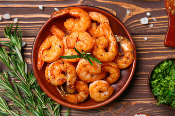 Plate of tasty shrimp tails and herbs on wooden background