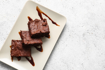 Plate with pieces of tasty chocolate brownie on white background