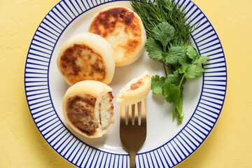 Plate with tasty cottage cheese pancakes on yellow background