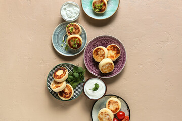 Plates with tasty cottage cheese pancakes and sauce on color background