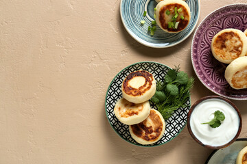Plates with tasty cottage cheese pancakes and sauce on color background