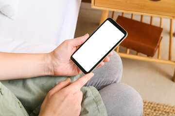 Woman using mobile phone with blank screen on bed at home, closeup