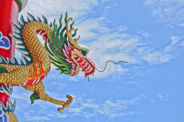 Golden flying majestic Asian Chinese dragonstatue with blue sky in sunny day