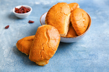 Bowl of tasty sochniki with cottage cheese on blue background