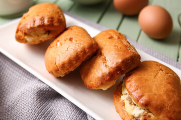 Plate of tasty sochniki with cottage cheese on green table, closeup