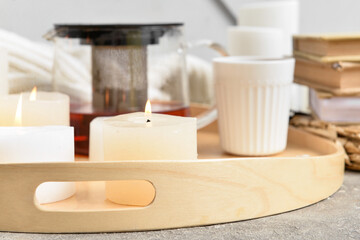 Fototapeta na wymiar Tray with burning candles and teapot on table, closeup