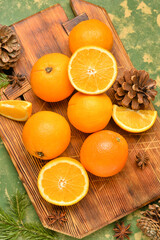 Wooden board with fresh oranges on green background