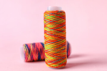 Rainbow sewing thread spools on color background
