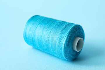 Blue sewing thread spool on color background