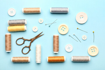 Fototapeta na wymiar Sewing thread spools, buttons, scissors and pins on color background