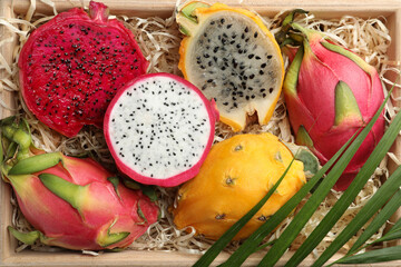 Delicious cut and whole dragon fruits in crate, top view