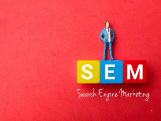 Top view miniature people with text SEM (Search Engine Marketing) on red background
