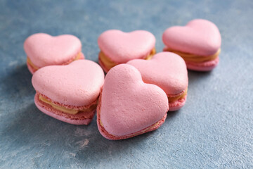 Tasty heart-shaped macaroons on blue background