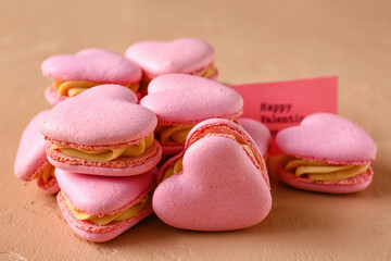 Tasty heart-shaped macaroons on beige background
