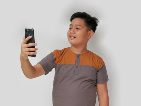 portrait of asian boy with smiling expression taking selfie, isolated at white background