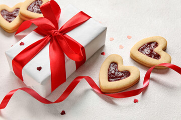 Tasty cookies in heart shape and gift box on light background