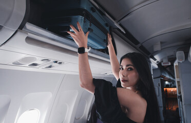 Portrait Asian woman tourist boarded the plane first class passenger a suitcase putting on floor near seat area ,travel on her holidays.