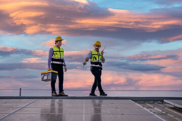 Engineers walking on roof inspect and check solar cell panel by hold equipment box and radio communication ,solar cell is smart grid ecology energy sunlight alternative power factory concept.