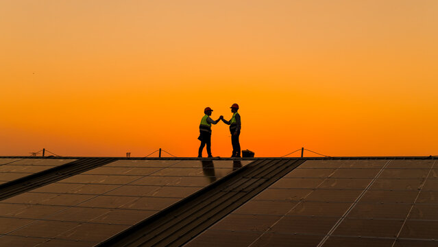 Engineers walking on roof inspect and check solar cell panel by hold equipment box and radio communication ,solar cell is smart grid ecology energy sunlight alternative power factory concept.