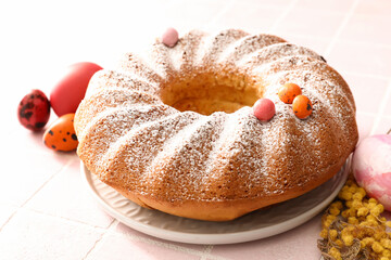 Plate with tasty Easter cake and eggs on tile background