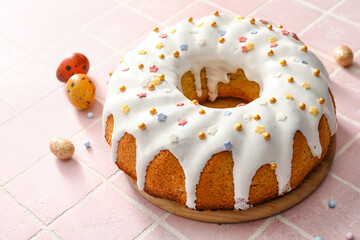 Wooden board with tasty Easter cake and eggs on tile background
