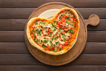 Board with tasty heart-shaped pizza on dark wooden background. Valentine's Day celebration