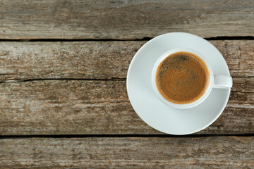 Cup of tasty coffee on wooden table, top view. Space for text