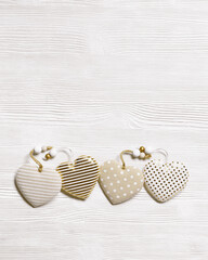 Valentines day concept. Four soft toy hearts from linen cloth with golden color striped or dots on white wooden table. Valentines Day background with copy space. Theme of love, top view