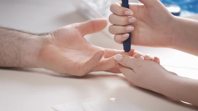Doctor making blood sugar test and checking blood sugar level of patient diabetes with lancet glucometer in fingertip. Medical and Treatment of diabetes concept. 4K