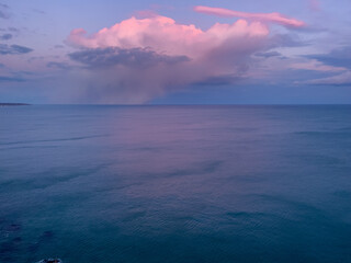 A large thundercloud on the horizon over the sea. 