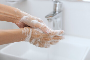 Washing hands under the flowing water tap. Hygiene concept hand detail. Washing hands rubbing with...