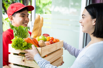 Asian delivery man deliver box of fruit and bread to young customer. 