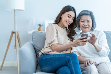 Asian lovely family, young daughter use mobile phone with older mother