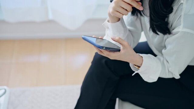 部屋でスマホを使う女性