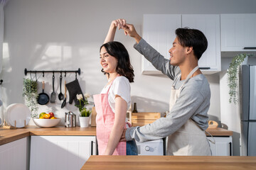 Asian attractive loving couple enjoy dance together in kitchen at home