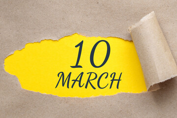 march 10. 10th day of the month, calendar date. Hole in paper with edges torn off. Yellow background is visible through ragged hole.Spring month, day of the year concept