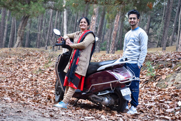 Fototapeta na wymiar mother and his son in long trips , this is the way of india family chill out time in winter vacation ,family holiday chill out time with your two wheeler and enjoy .