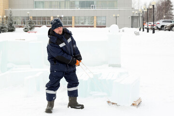 Fototapeta na wymiar A worker carries ice blocks on a sled.