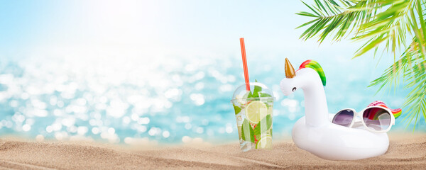 Fresh cold mojito cocktail, inflatable unicorn toy and sunglasses