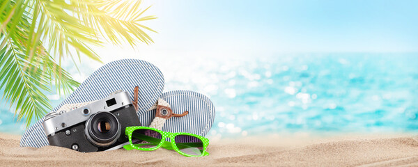 Retro camera, flip-flops and sunglasses on tropical beach