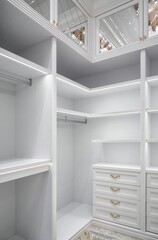 White corner wardrobe section with empty rack and led illumination on shelves in spacious walk-in closet in luxury apartment