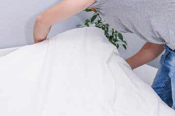 A man puts an elasticated sheet on the mattress. Change of bed linen.