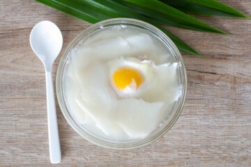 Top view of Egg and young coconut in coconut water in a cup is a Thai dessert on table.