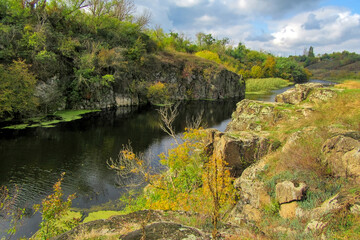 Fototapeta na wymiar Vertical stone rocks on the bank of the river. A picturesque view of the Tyasminsky canyon with river on sunny day. Kam'yanka Cherkasy region, Ukraine.