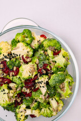 A salad made of broccoli. Dried cranberries and sunflower seeds are topping.