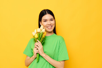 woman with Asian appearance green t-shirt a bouquet of yellow flowers yellow background unaltered