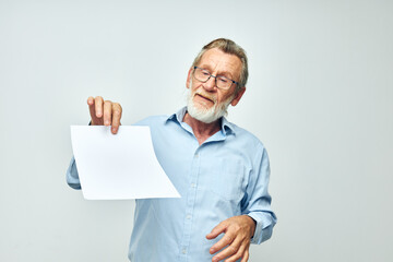 Portrait of happy senior man in a blue shirt and glasses a white sheet of paper cropped view